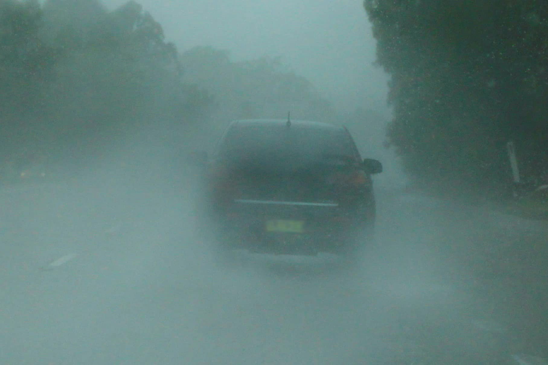 Car driving on road with heavy rain and limited visibility